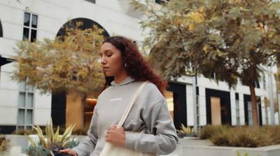 a woman is walking down the street with a handbag