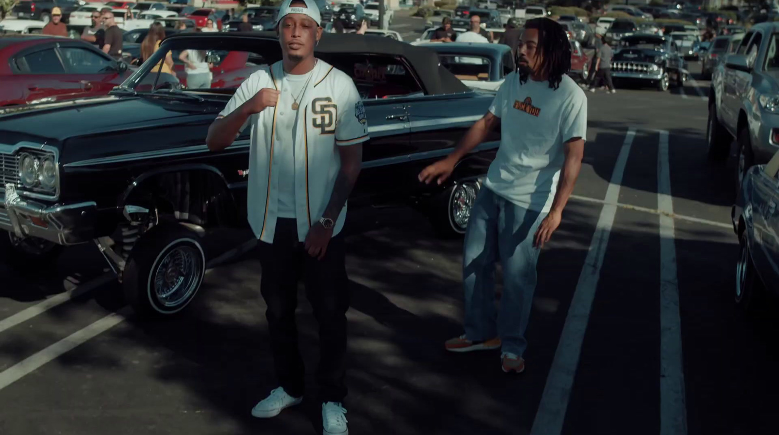 two men standing next to a car in a parking lot