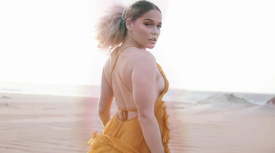 a woman in a yellow dress walking on a beach