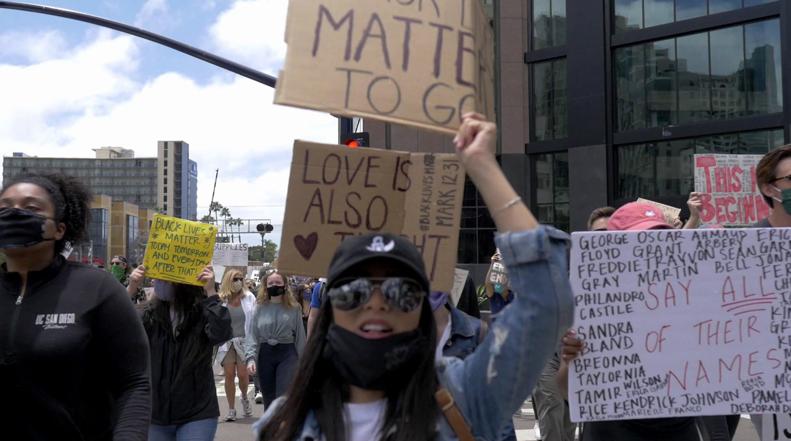 a group of people walking down a street holding signs