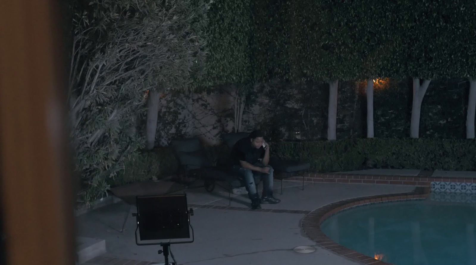 a man sitting in a chair next to a pool at night