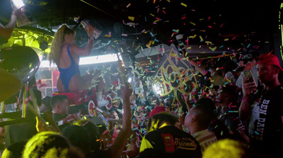 a woman in a bikini standing on a stage surrounded by confetti