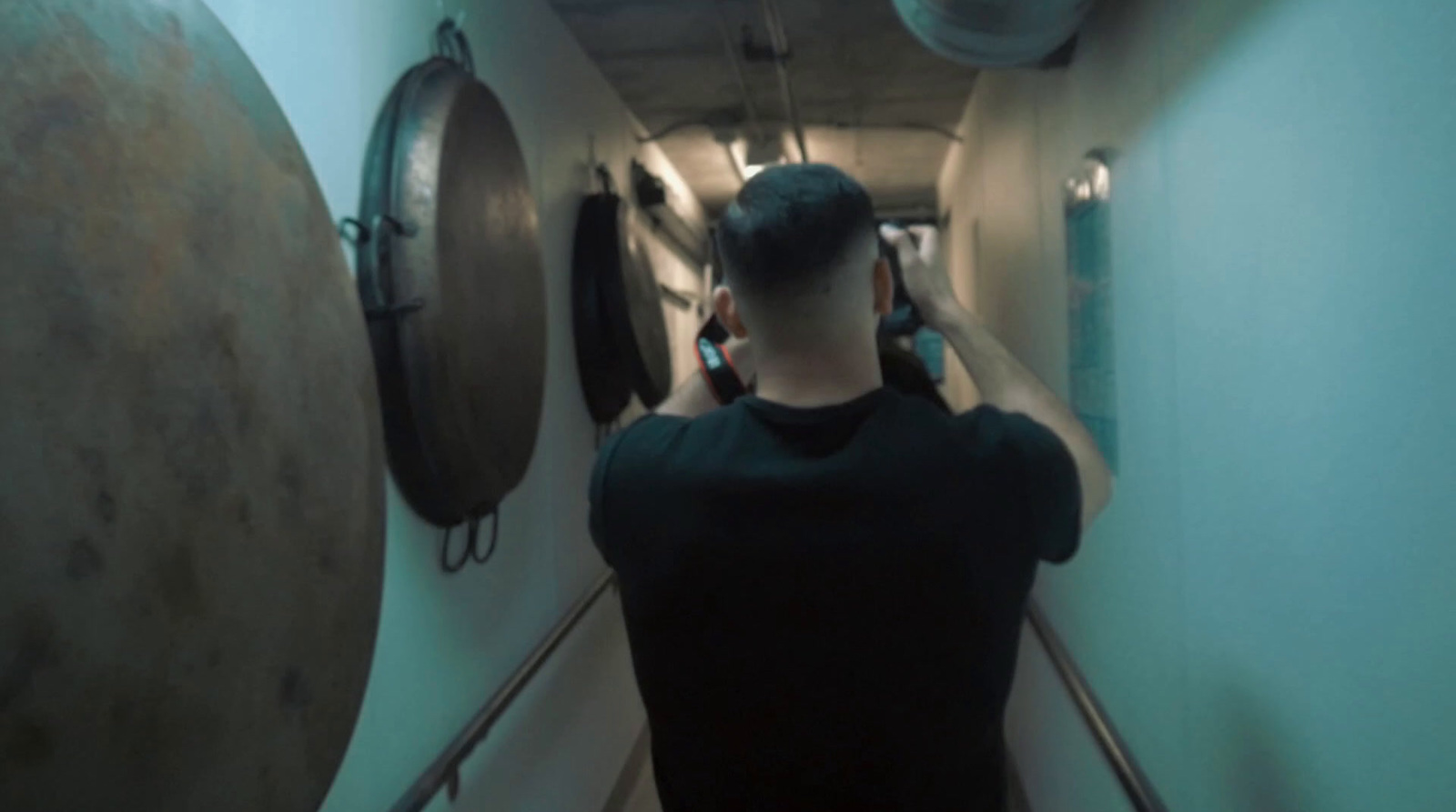 a man in a black shirt is walking down a hallway