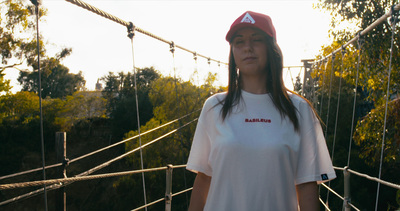 a woman standing on a rope bridge with trees in the background