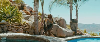 a woman standing next to a pool surrounded by palm trees