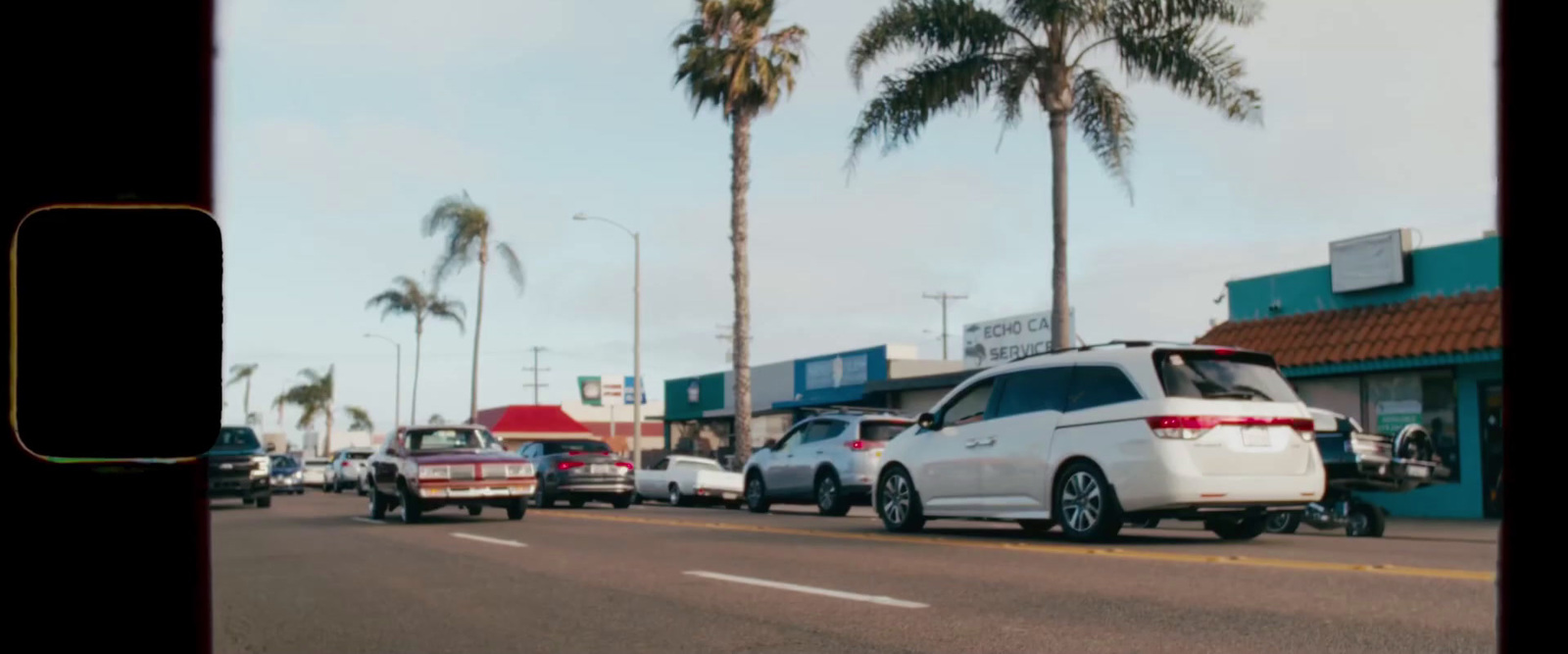 a white van driving down a street next to tall palm trees