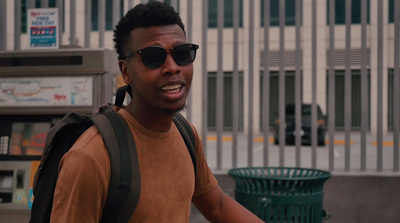 a man with a backpack and sunglasses walking down the street