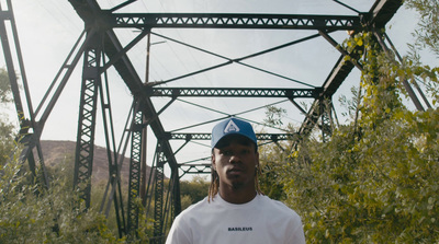 a man standing in front of a metal bridge