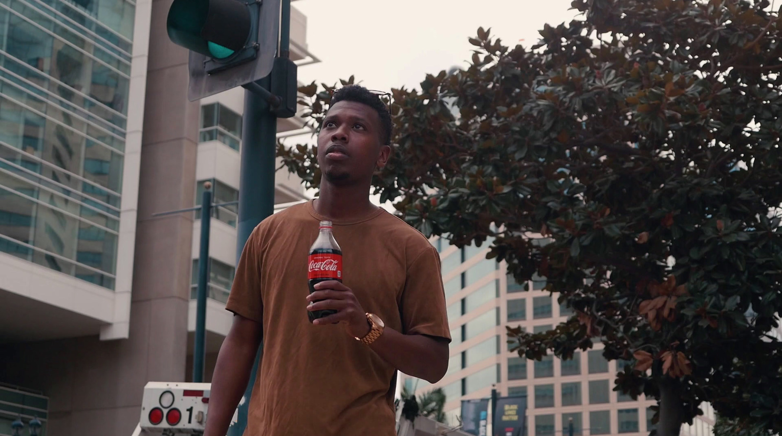 a man standing under a traffic light holding a bottle