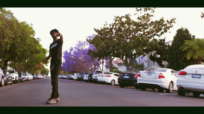 a man riding a skateboard down a street next to parked cars