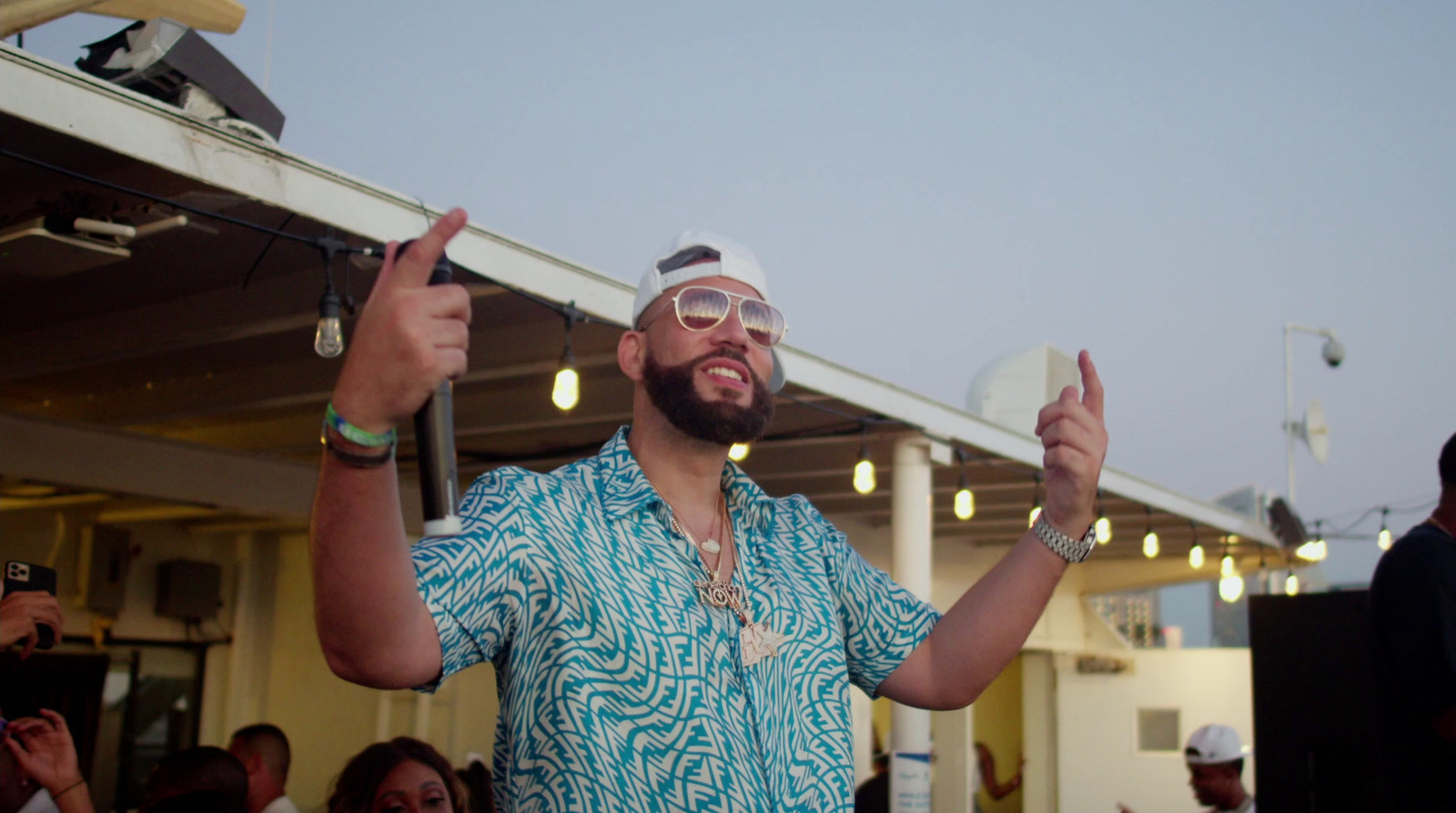 a man in a blue shirt and sunglasses giving a thumbs up