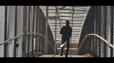 a man walking across a bridge over water