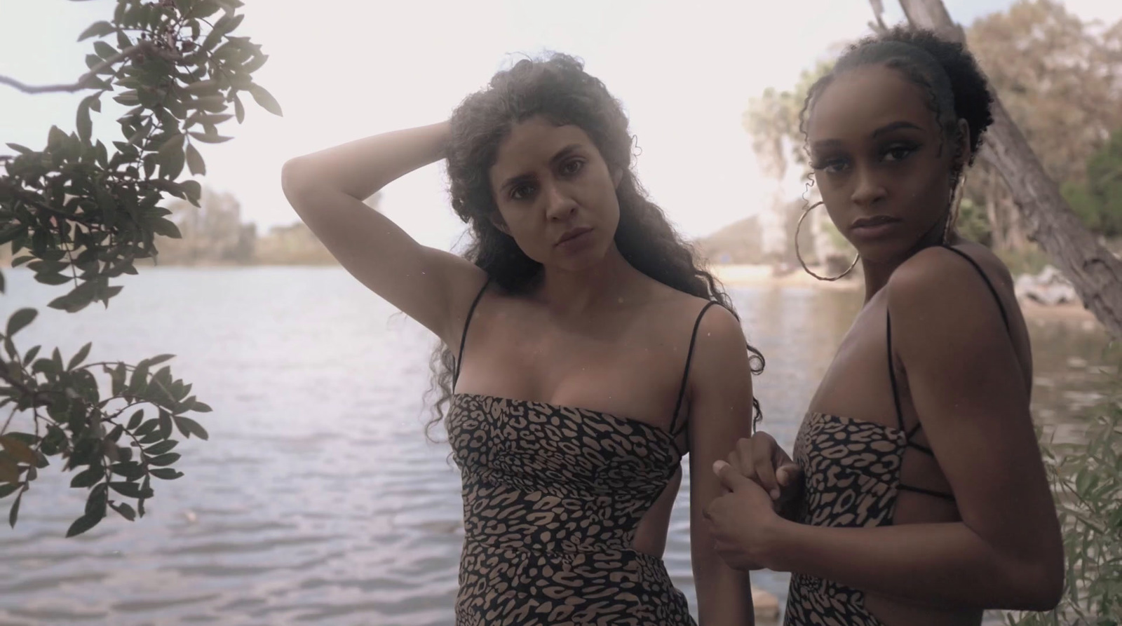 two women standing next to each other near a body of water