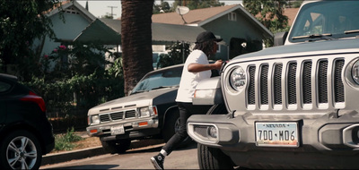 a man walking past a parked jeep on a street