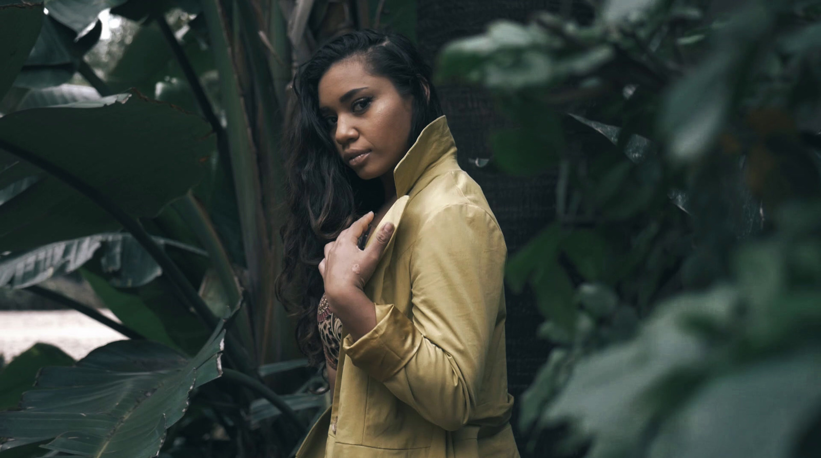 a woman in a yellow jacket standing in a jungle