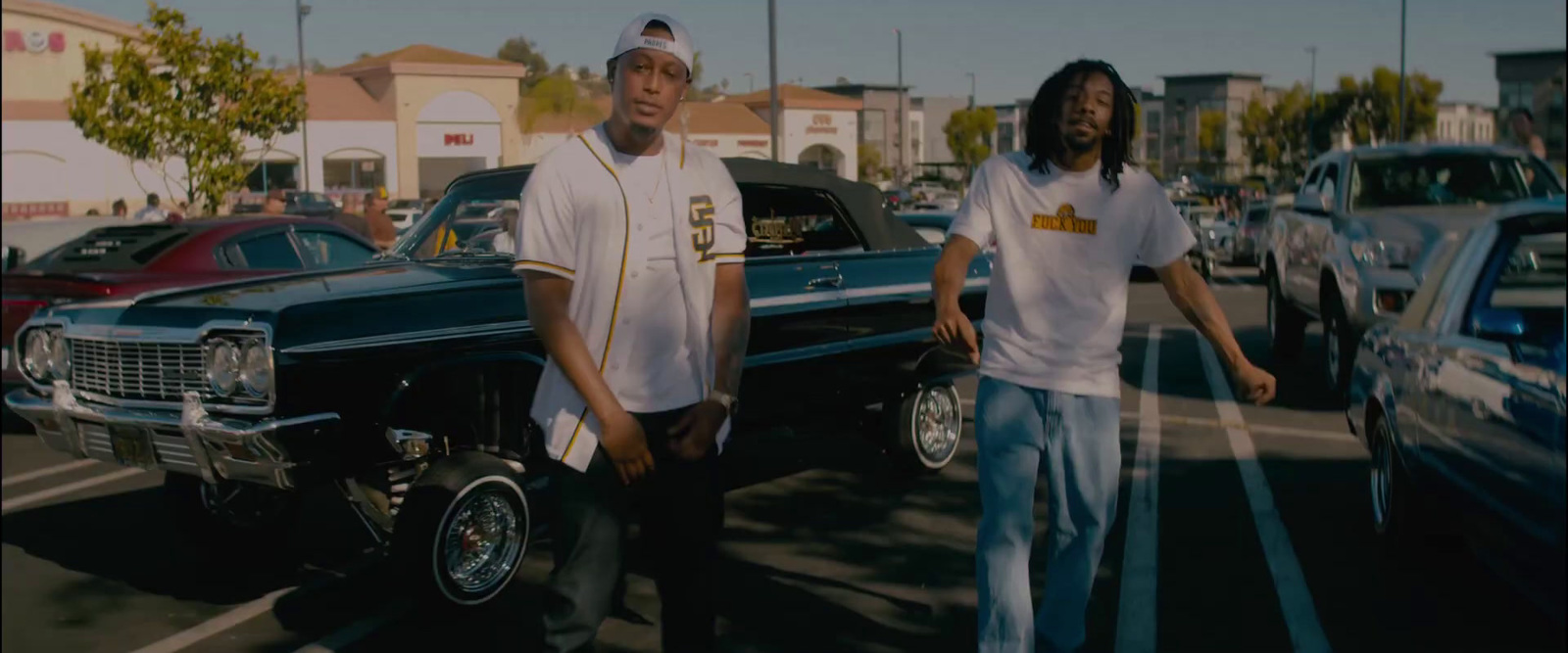 two men standing next to each other in a parking lot