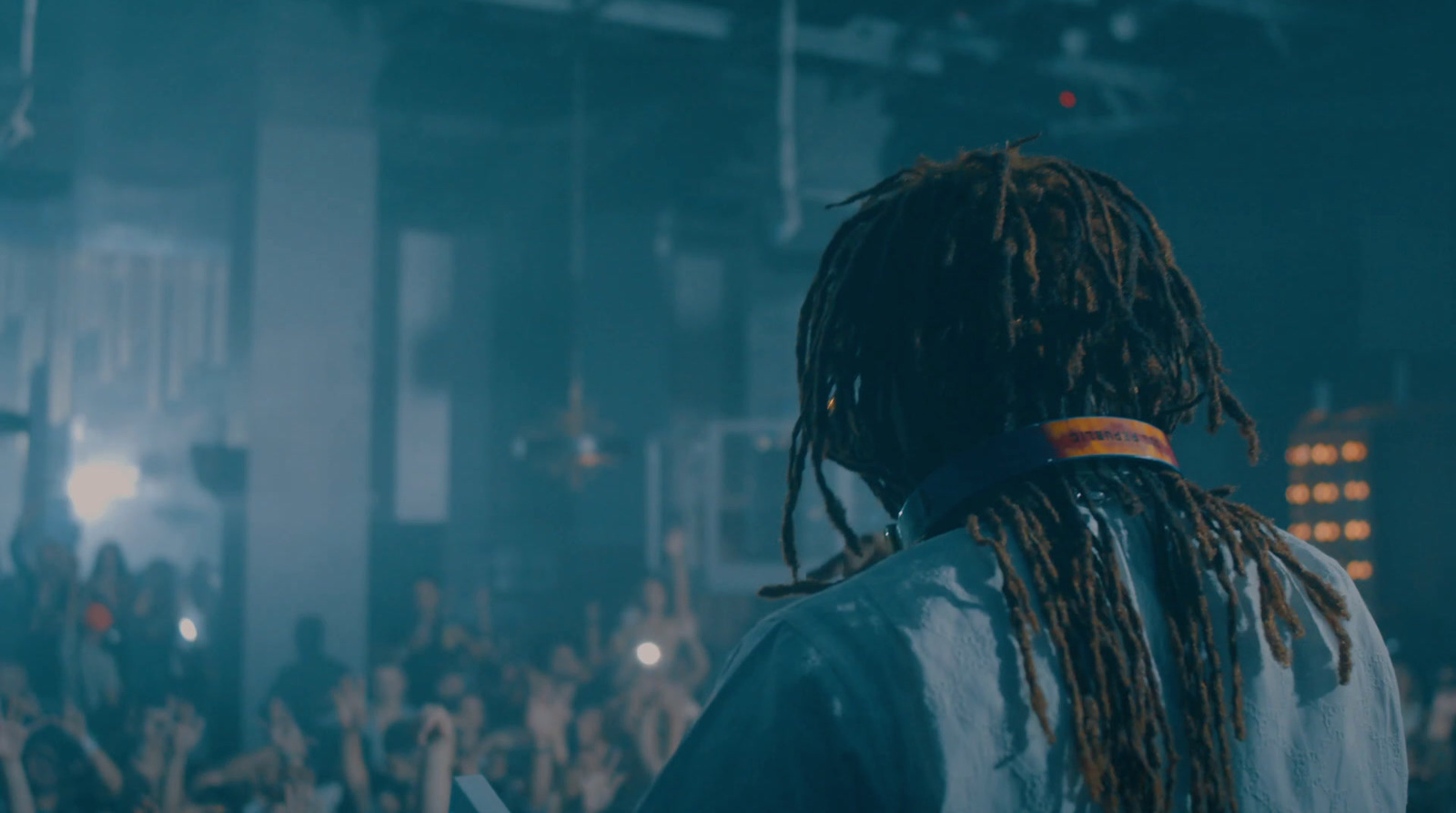 a man with dreadlocks standing in front of a crowd