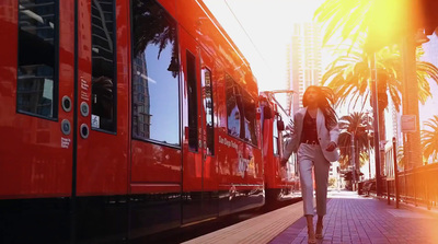 a woman walking down a sidewalk next to a red train