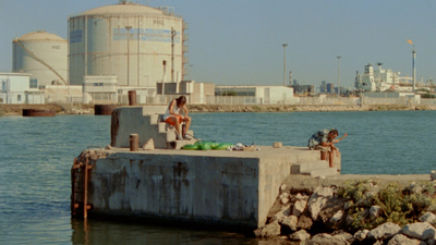 a couple of people sitting on top of a cement pier