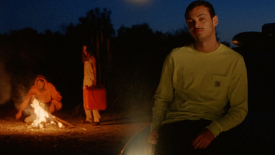 a man sitting in front of a campfire at night