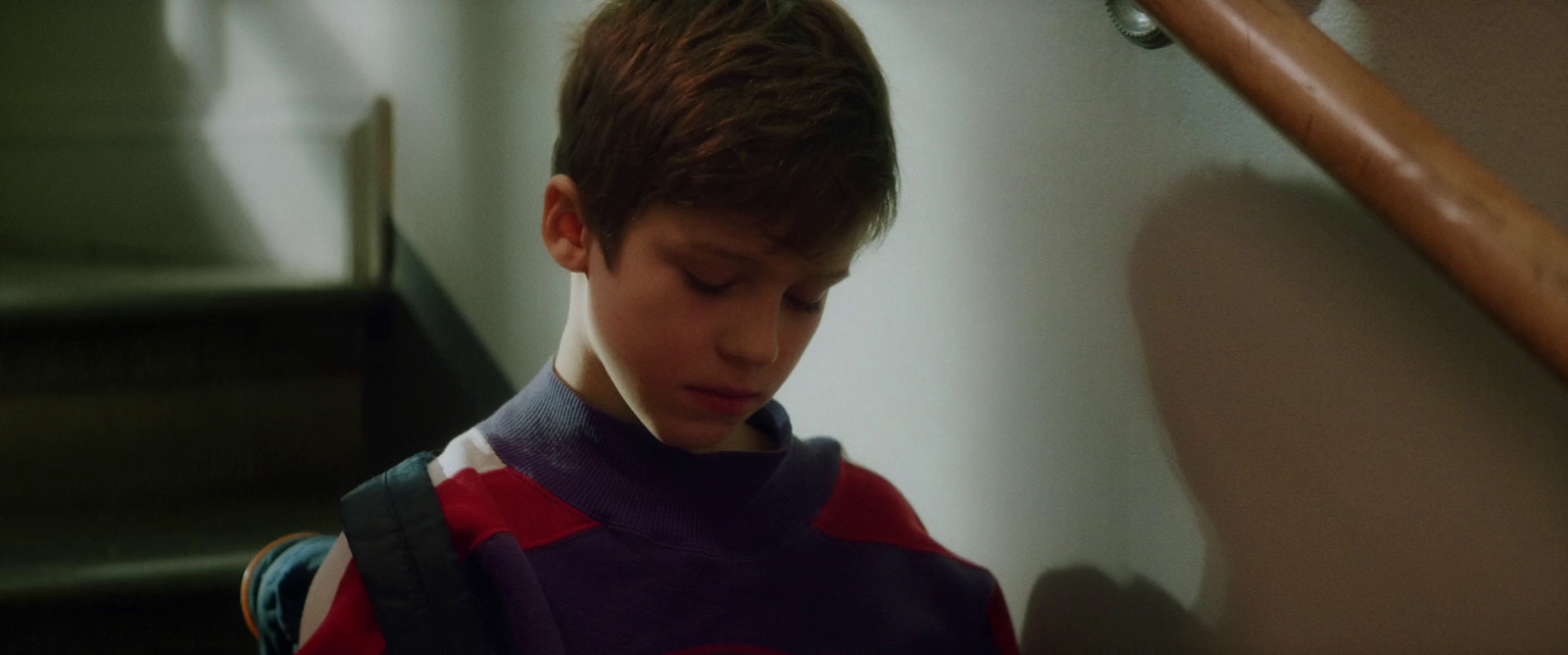 a boy in a purple shirt is sitting on a stairway