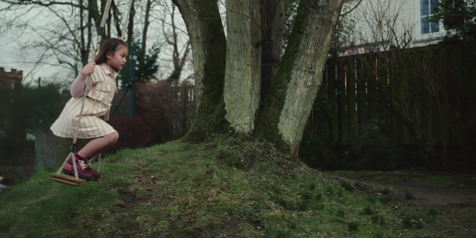 a girl in a dress swinging on a tree