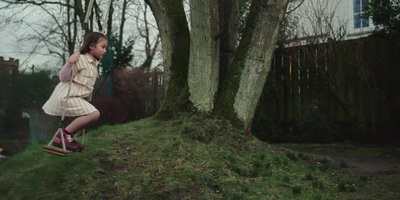 a girl in a dress swinging on a tree