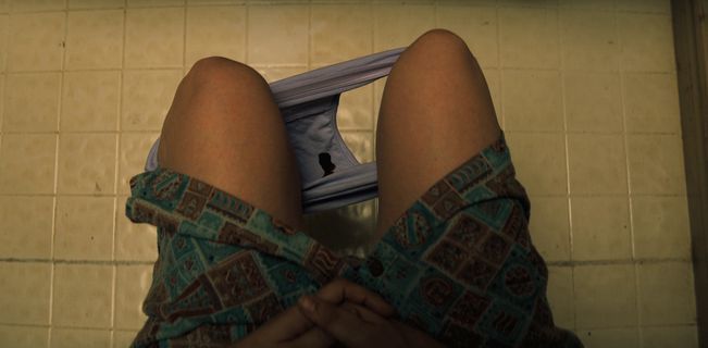 a woman's legs are sitting on the floor in a bathroom