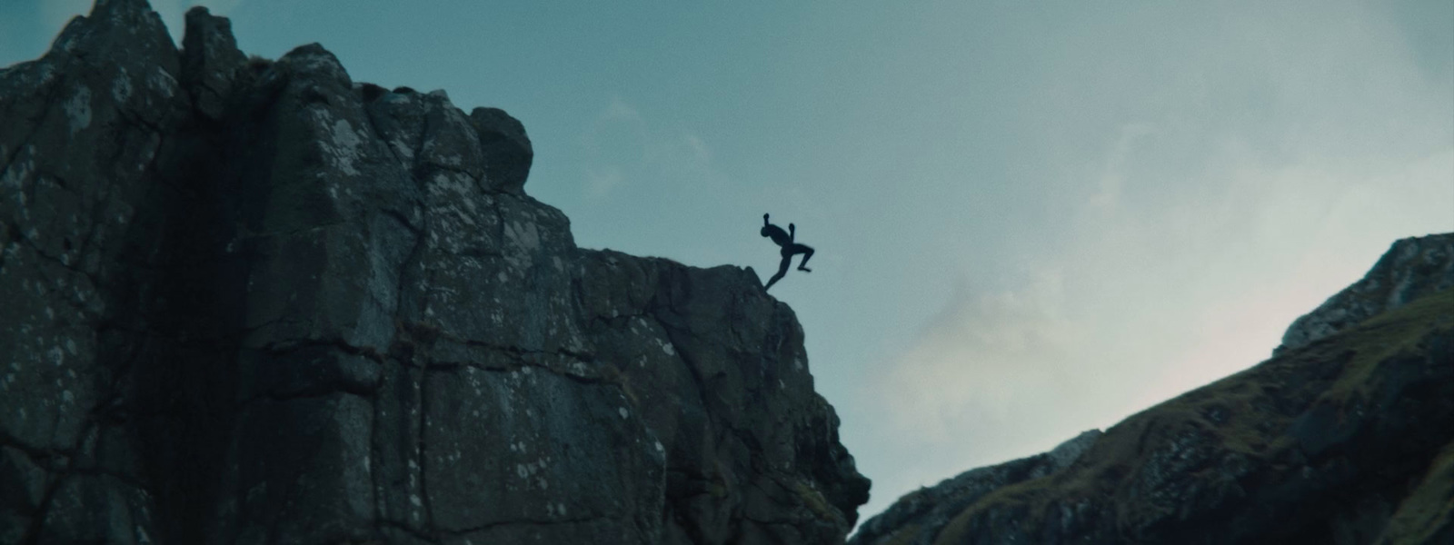 a man is standing on the edge of a cliff