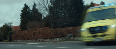 a yellow ambulance driving down a street