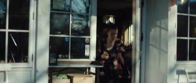 a woman is standing in the doorway of a shop