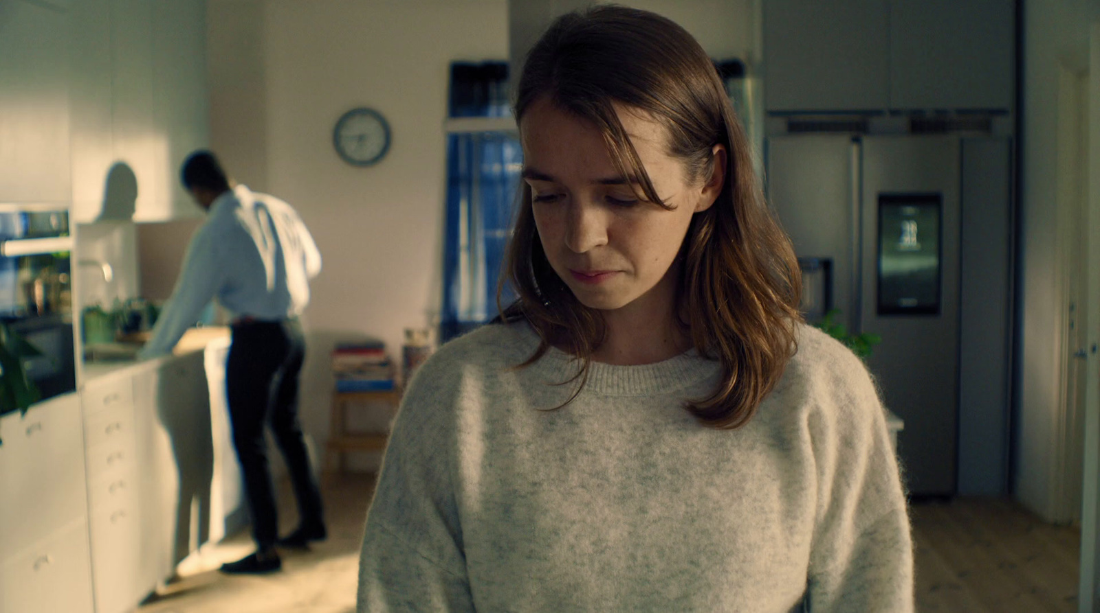 a woman in a white sweater standing in a kitchen