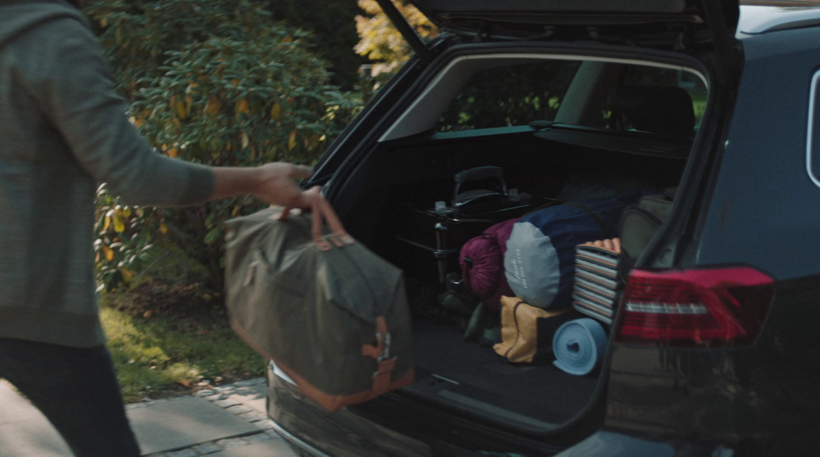 a woman is loading her luggage into the back of a car