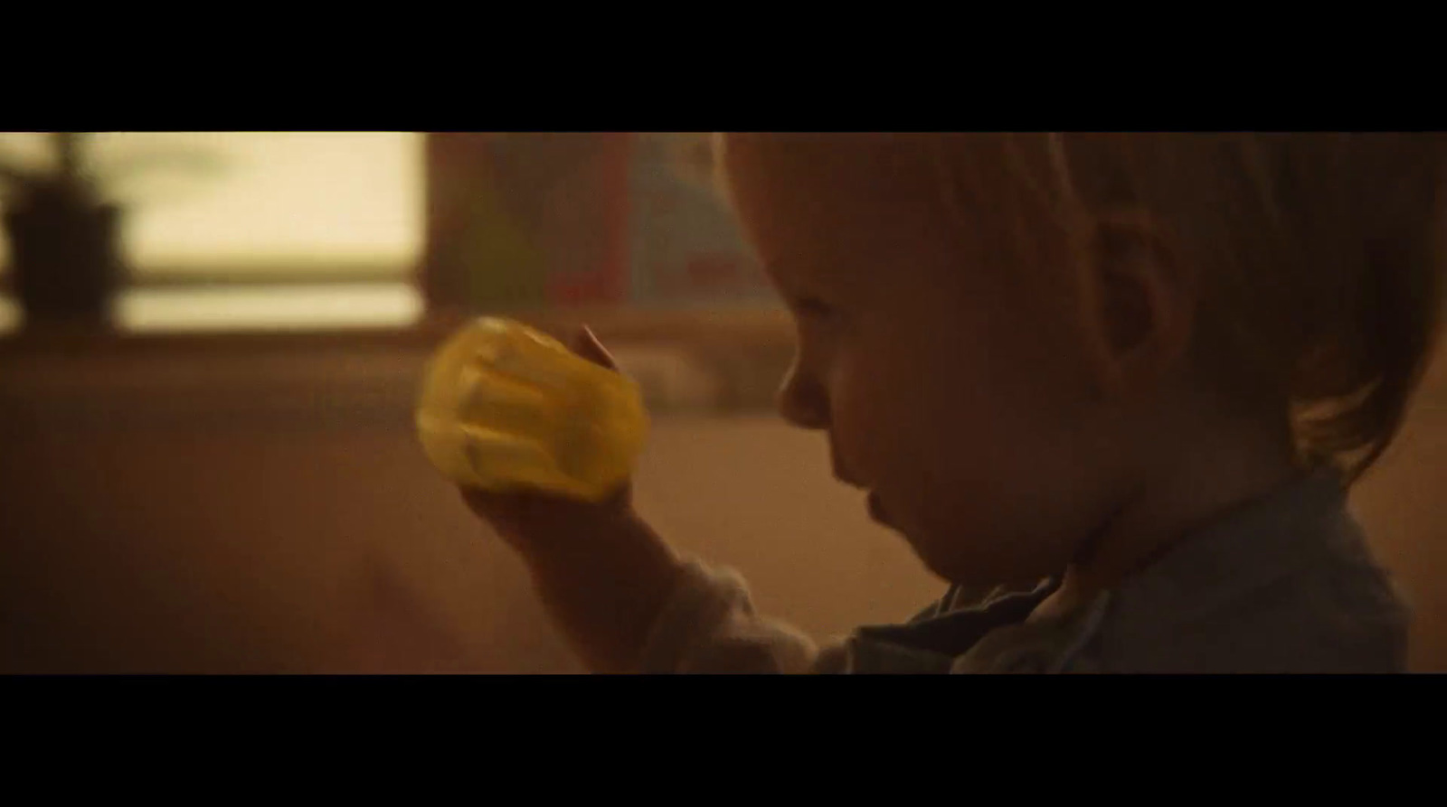 a child is holding a yellow cup in his hand