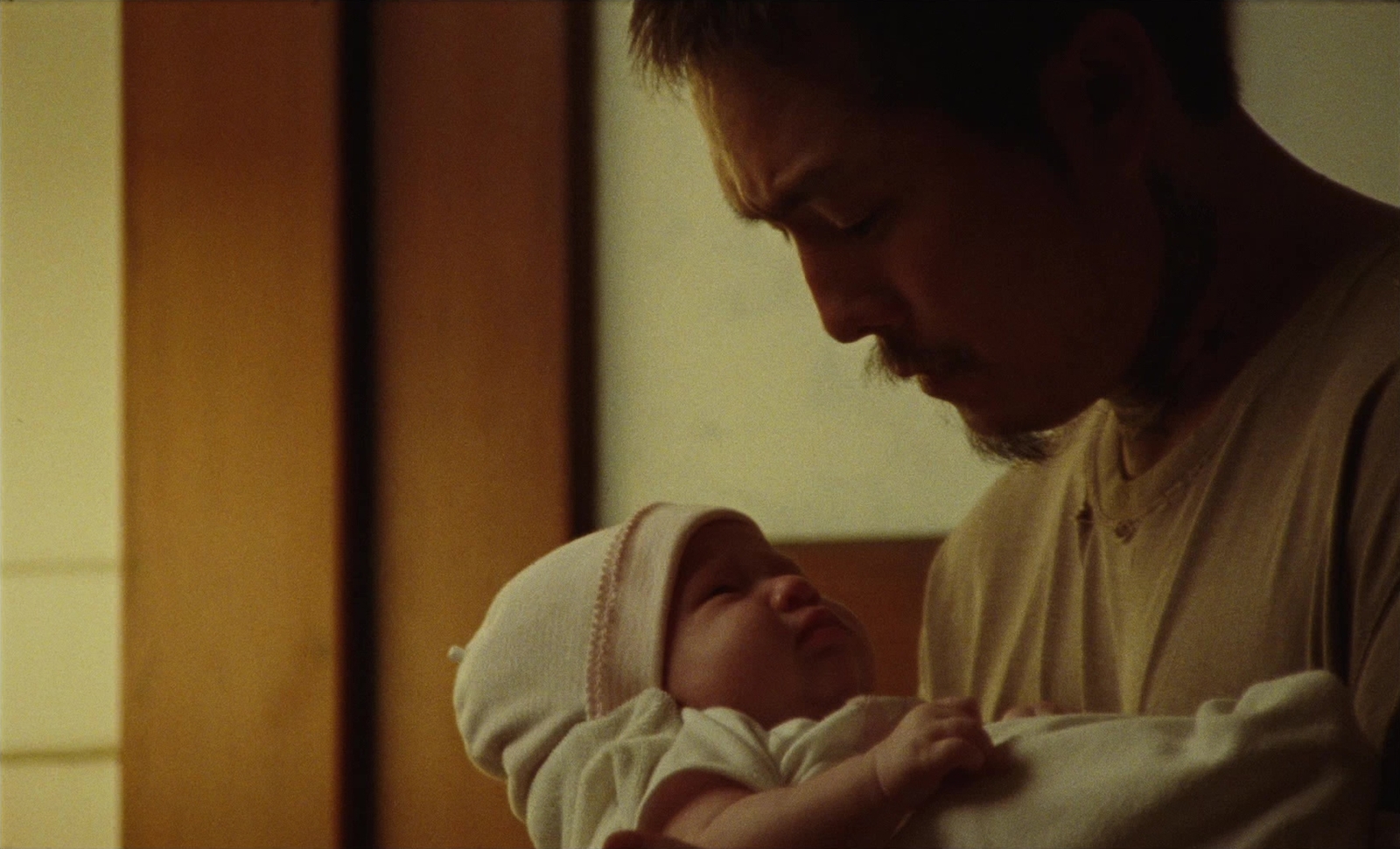 a man holding a baby in front of a window