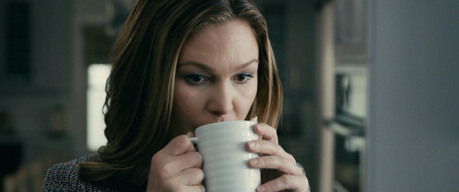 a woman drinking a cup of coffee in a kitchen