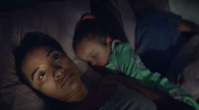 a woman and a child laying in bed at night