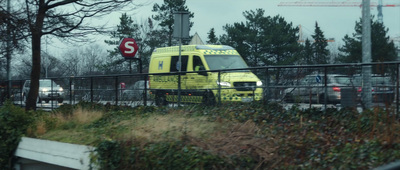 a yellow ambulance driving on a bridge