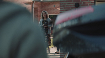 a woman is standing in front of a brick house