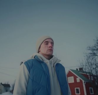 a man in a blue vest standing in front of a house