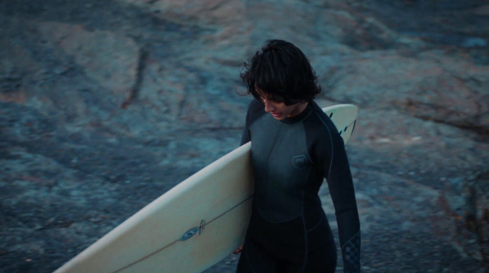 a man in a wet suit carrying a surfboard