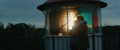 a man and woman standing in front of a lighthouse