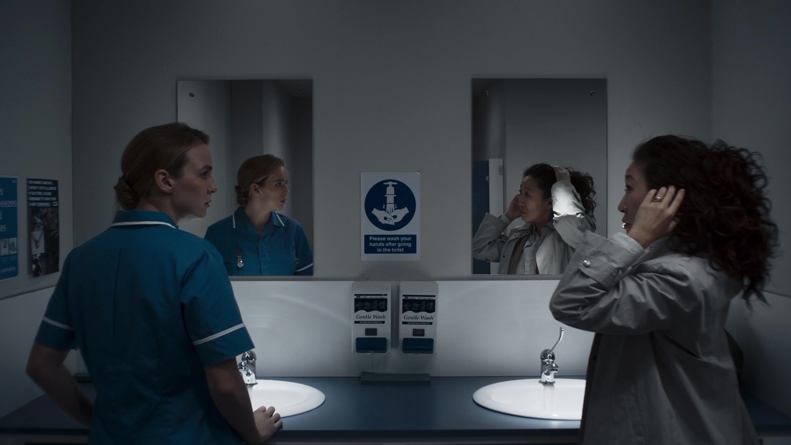 two nurses looking at mirrors in a bathroom