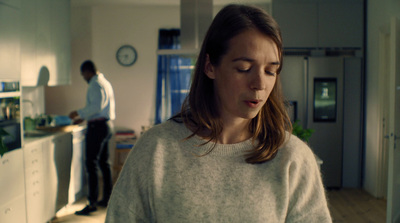 a woman in a white sweater standing in a kitchen