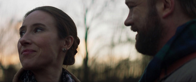 a man and woman looking at each other in the woods