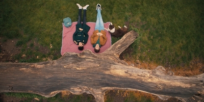 two people laying on a blanket next to a tree