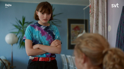 a young woman is standing in a room with her arms crossed