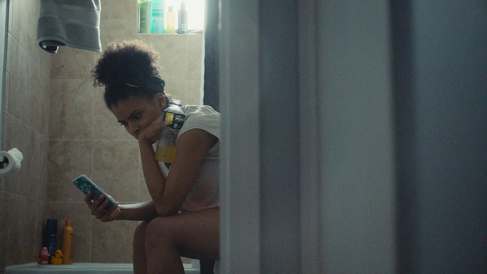 a woman sitting in a bathroom looking at her phone