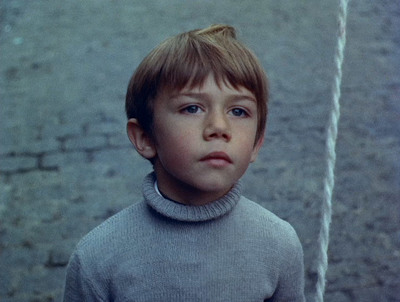 a young boy in a gray sweater looking at a rope