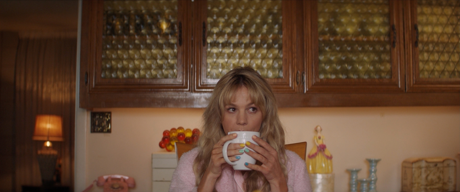 a woman drinking a cup of coffee in a kitchen